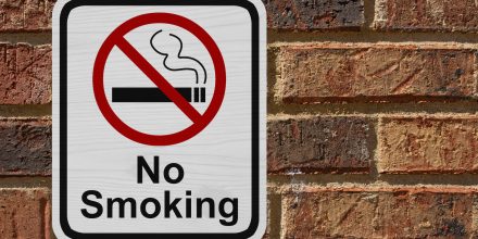 No Smoking Sign, Red and White sign with words No Smoking and cigarette symbol on a brick wall