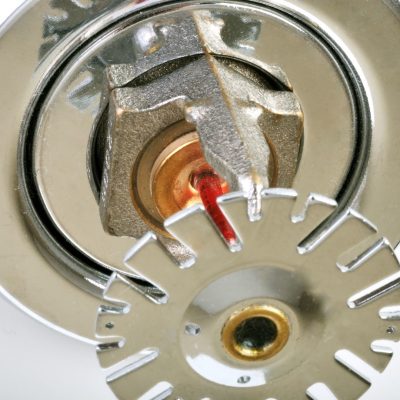 Close up image of fire sprinkler on white. Fire sprinklers are part of an integrated water piping system designed for life and fire safety.